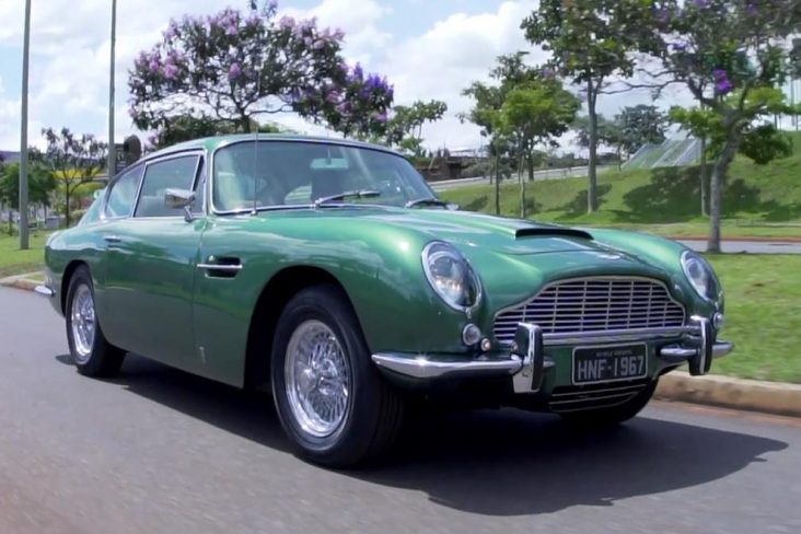 Aston Martin DB6 1967 verde rodando próximo a praça