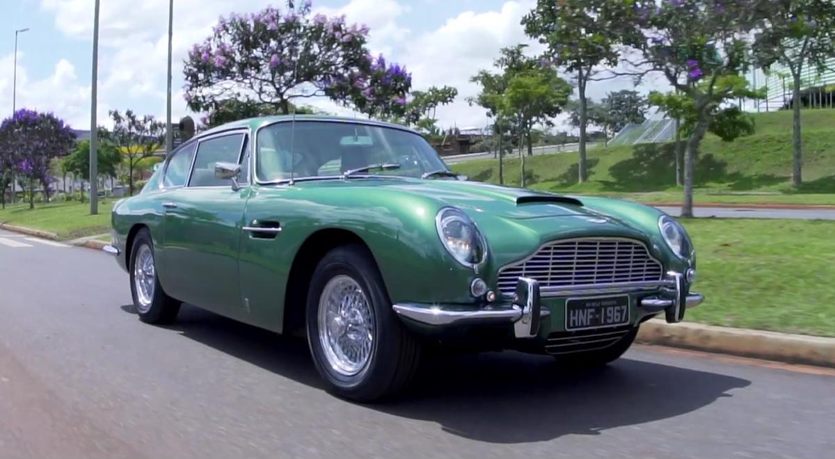 Aston Martin DB6 1967 verde rodando próximo a praça