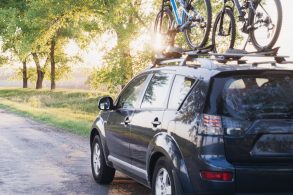 Mitsubishi Outlander cinza transportando duas bicicletas no suporte de teto