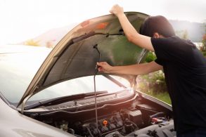 pessoa abrindo o capô do carro para verificar algum problema no motor