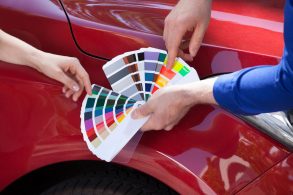 mãos colocam paleta de cor sobre a pintura de carro vermelho