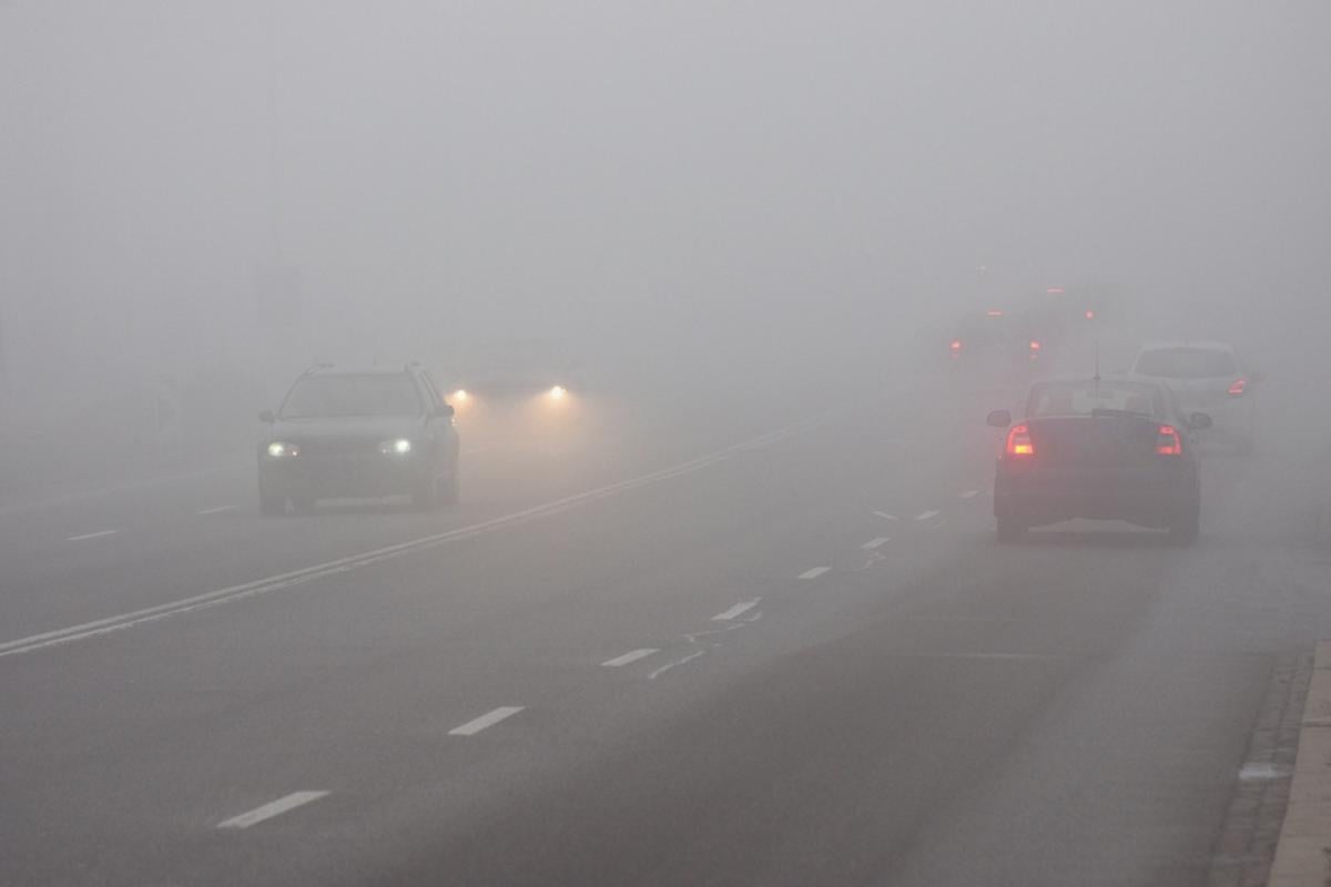 Dirigir carro com faróis baixos no meio da neblina na estrada