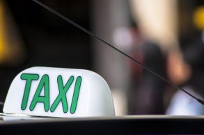 placa taxi no teto de veículo com cidade desfocada ao fundo