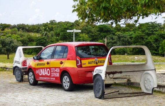volkswagen up vermelho de autoescola estacionado entre dois carros