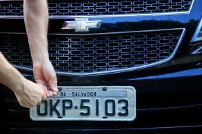 homem instalando a placa de identificacao veicular piv cinza