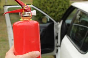 motorista segurando extintor incendio com carro automovel ao fundo