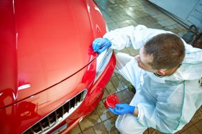 homem com pincel nas maos restaura pintura de carro vermelho