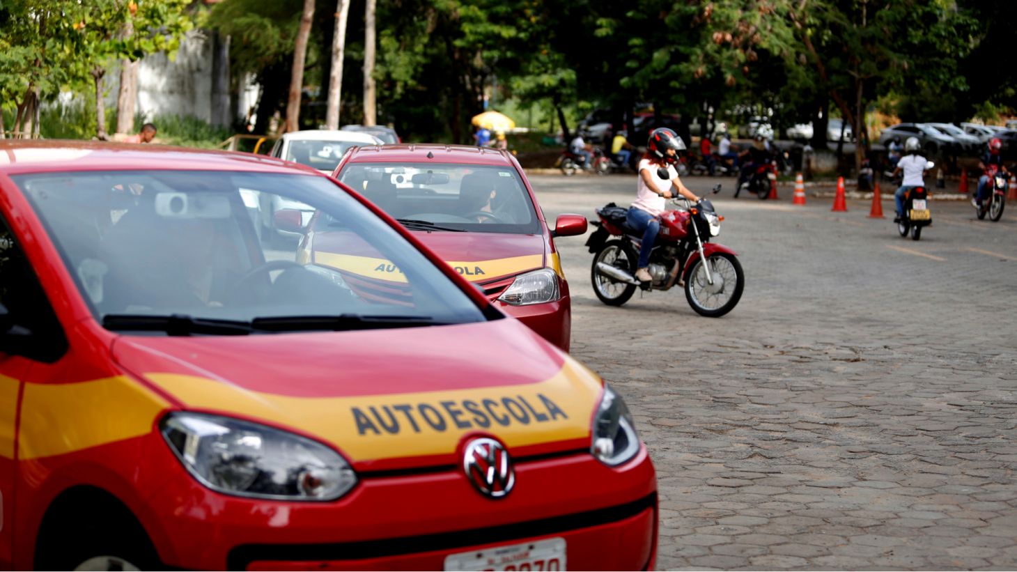 Carros de autoescola sendo dirigidos por candidatos à tirar a CNH