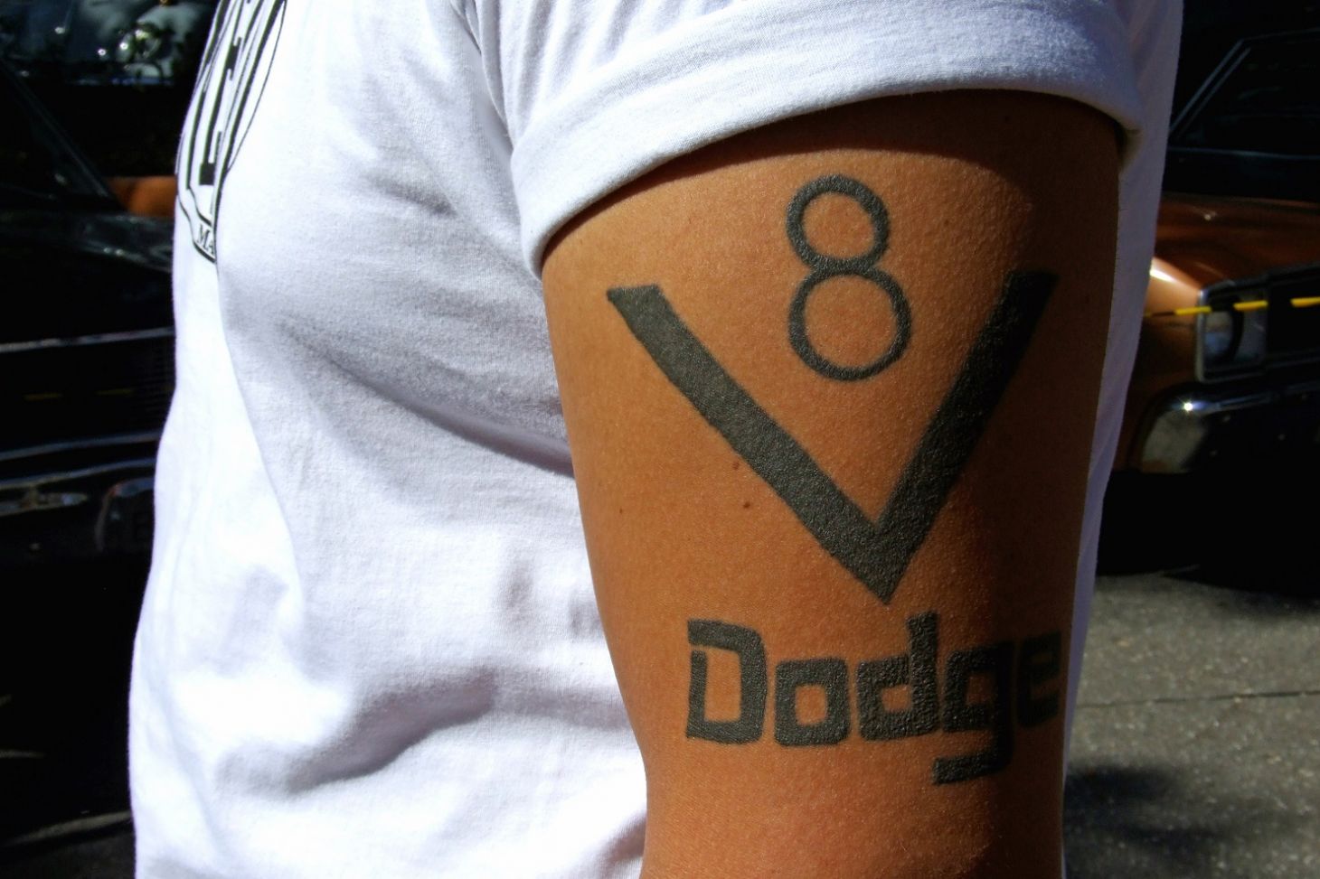 homem com tatuagem exaltando motor v8 da marca dodge