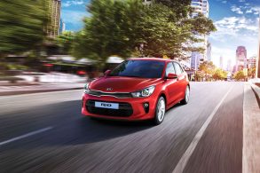Kia Rio na cor vermelha com a dianteira em detalhe em movimento na estrada