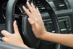 mao feminina acionando a buzina no volante de carro