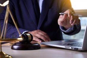 homem de terno com mao no computador indicando autenticacao de documentos de veiculos online