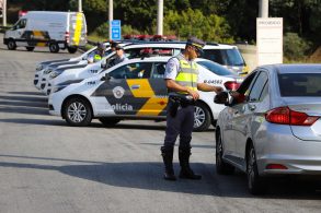 policial militar da cptran de sao paulo com documentos de motorista nas maos em fiscalizacao de transito com viaturas atras fotos governo de sao paulo