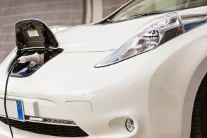 carro elétrico branco com carregador ligado na tomada