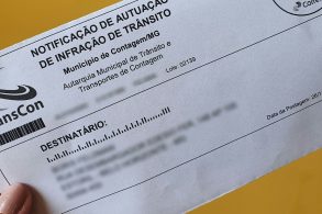 mulher segurando notificacao de autuacao de infracao de transito emitida pela transcon