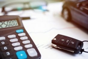 calculadora e chave de carro em cima de contrato