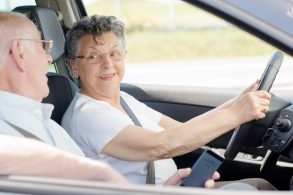 mulher idosa ao volante de carro com passageiro idoso ao lado