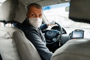 motorista profissional de mascara olhando para o banco de tras