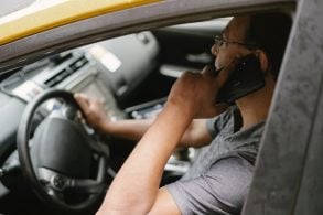 Motorista desatento no trânsito segurando volante com apenas uma mão