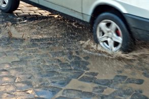 carro transita sobre calcamento irregular com pocas de agua e submete suspensao a esforcos foto shutterstock