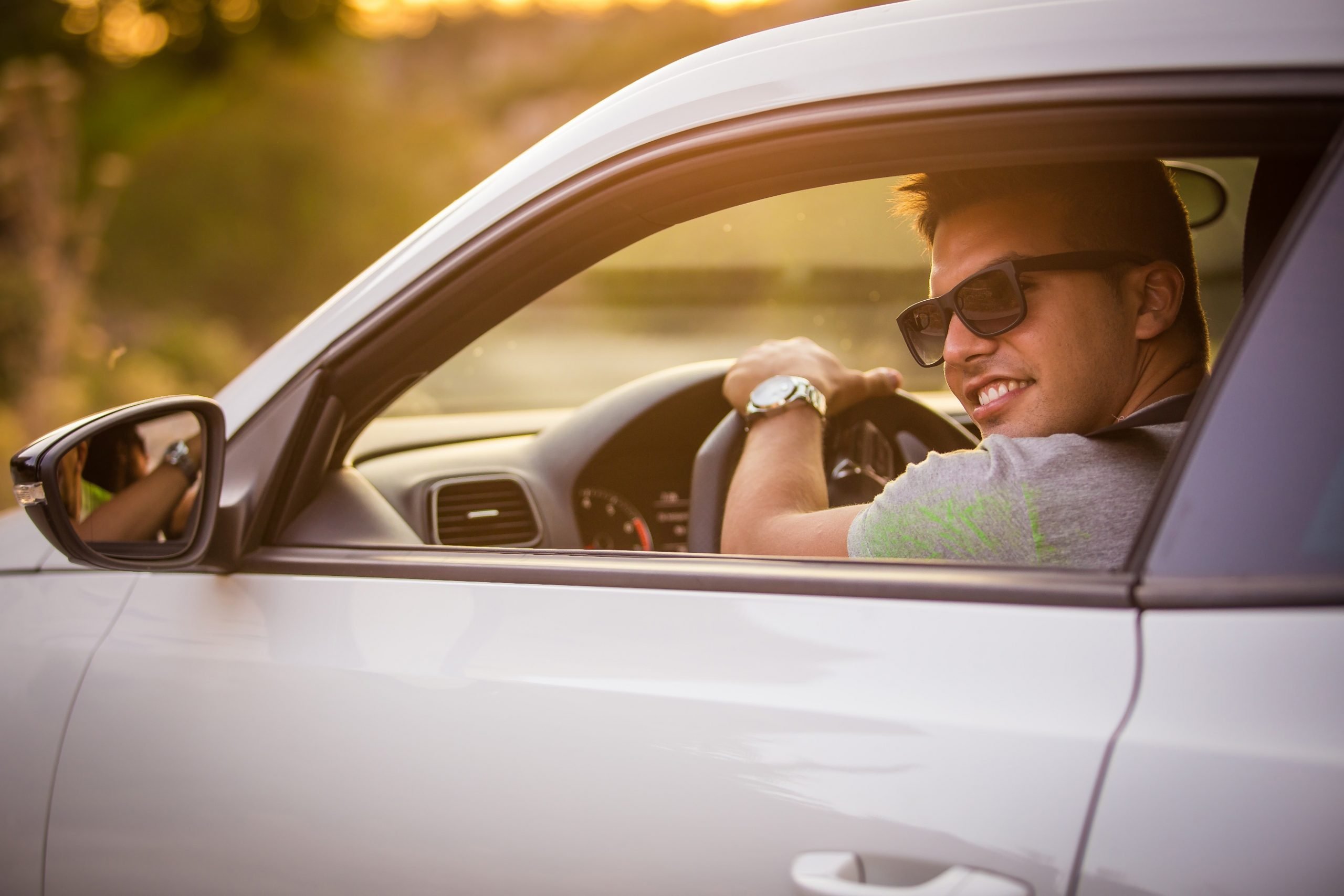 motorista jovem de oculos escuros dirigindo carro esportivo