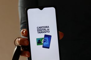 homem segura chave do carro e celular com aplicativo carteira digital de transito aberto