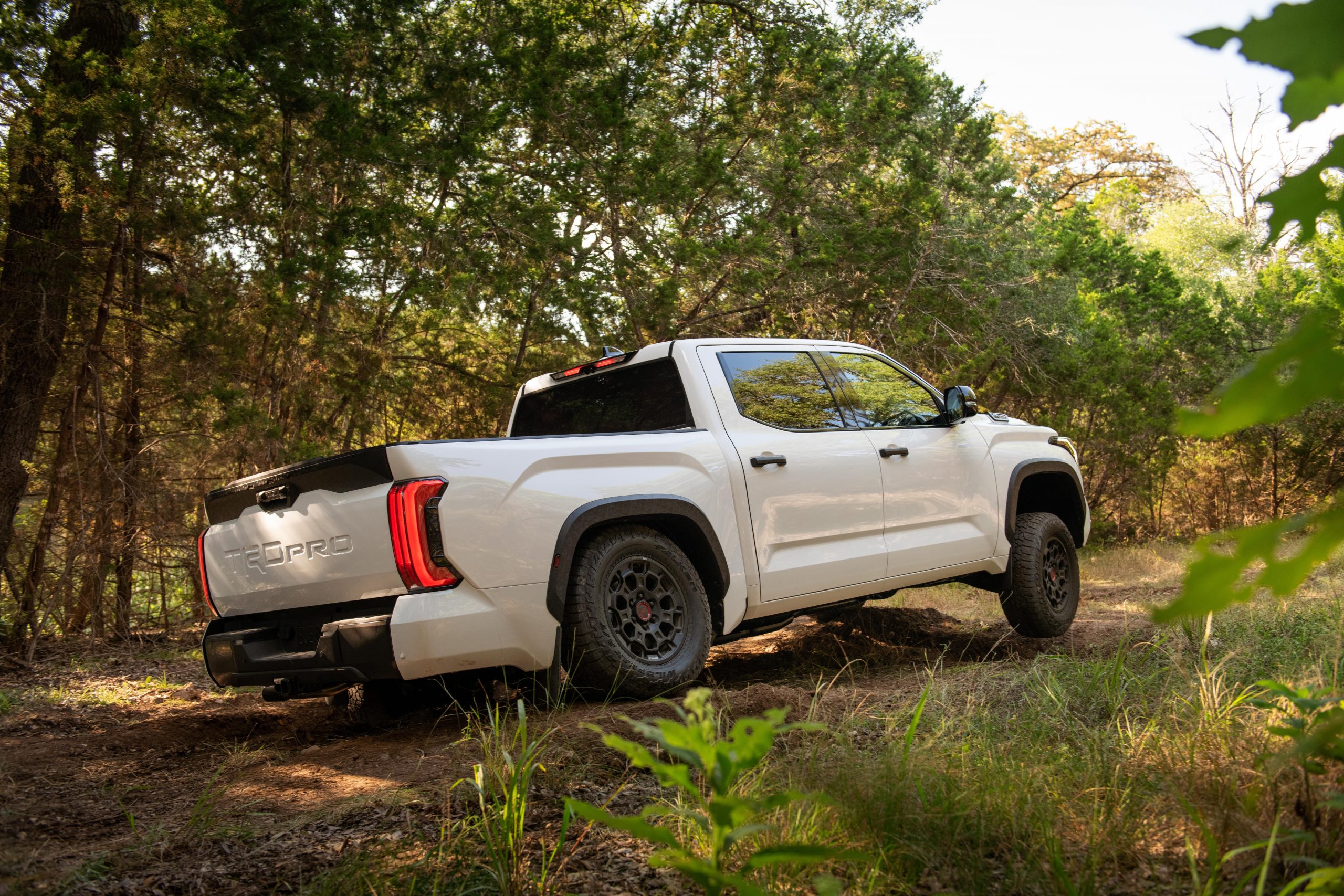 toyota tundra trd pro crewmax branco traseira em trilha dando fim de curso na suspensao