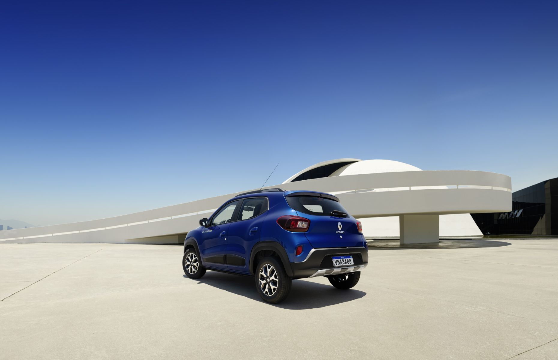 traseira do renault kwid outsider 2023 azul em frente a obra arquitetonica