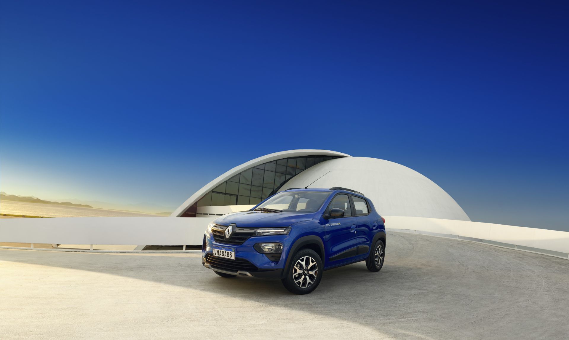 renault kwid outsider azul visto de lado em frente a obra arquitetonica