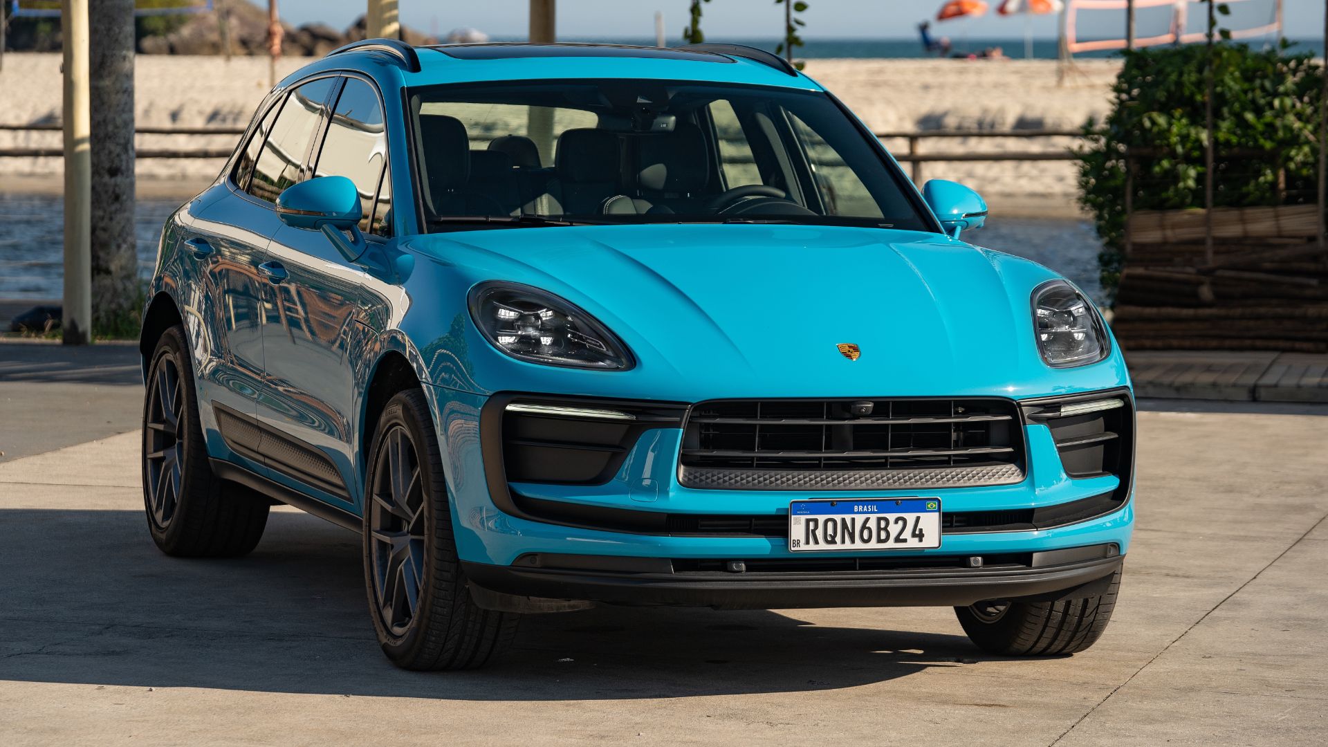 porsche macan 2023 azul miami frente parado com praia ao fundo