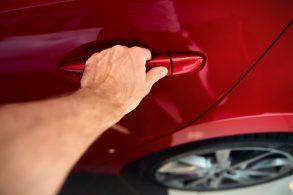 shutterstock mao masculina tocando macaneta de carro vermelho