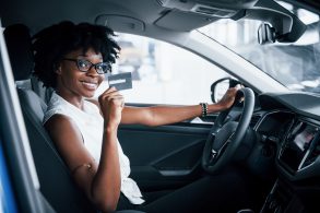 mulher dentro de carro com cartao de credito