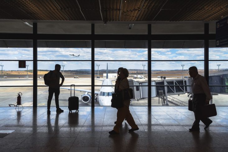 shutterstock area de embarque aeroporto de confins mg com pessoas em primeiro plano e aviao embraer e 190 da azul ao fundo