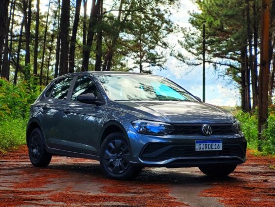 volkswagen polo track 2023 cinza platinum frente parado em estrada de interior com arvores ao fundo e folhas caidas na pista 2