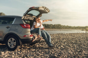 casal feliz sentado no porta malas de suv