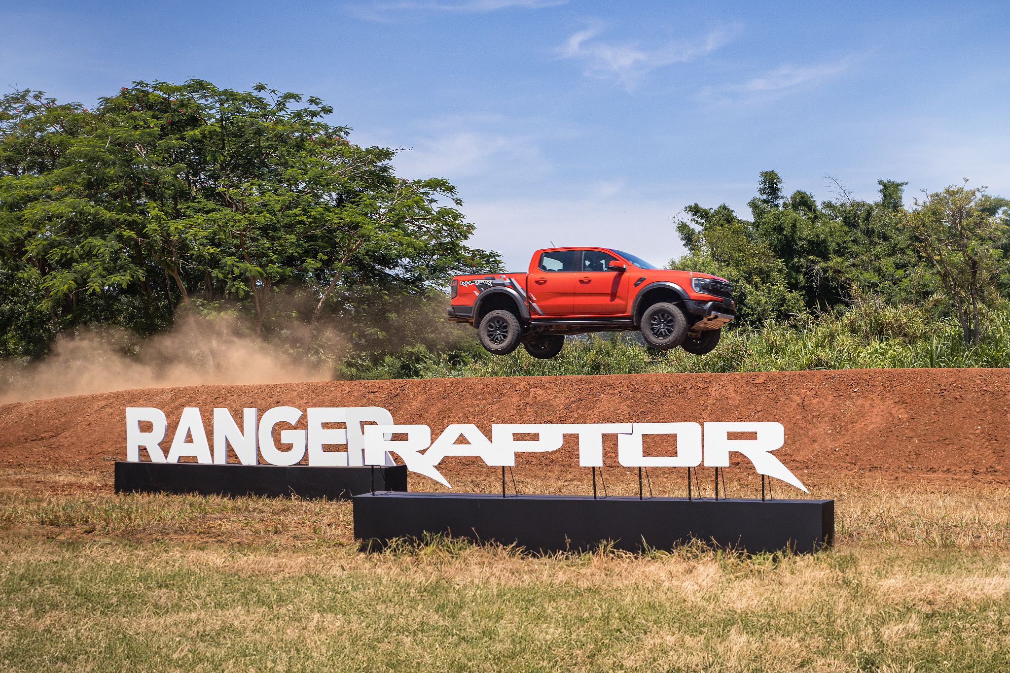 ford ranger raptor 2024 laranja saara lateral saltando com nome da picape em priemiro plano