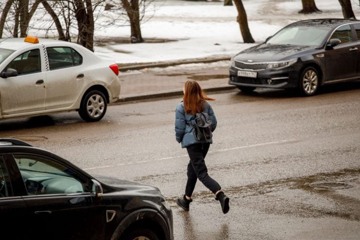 pedestre atravessando a rua meio aos carros