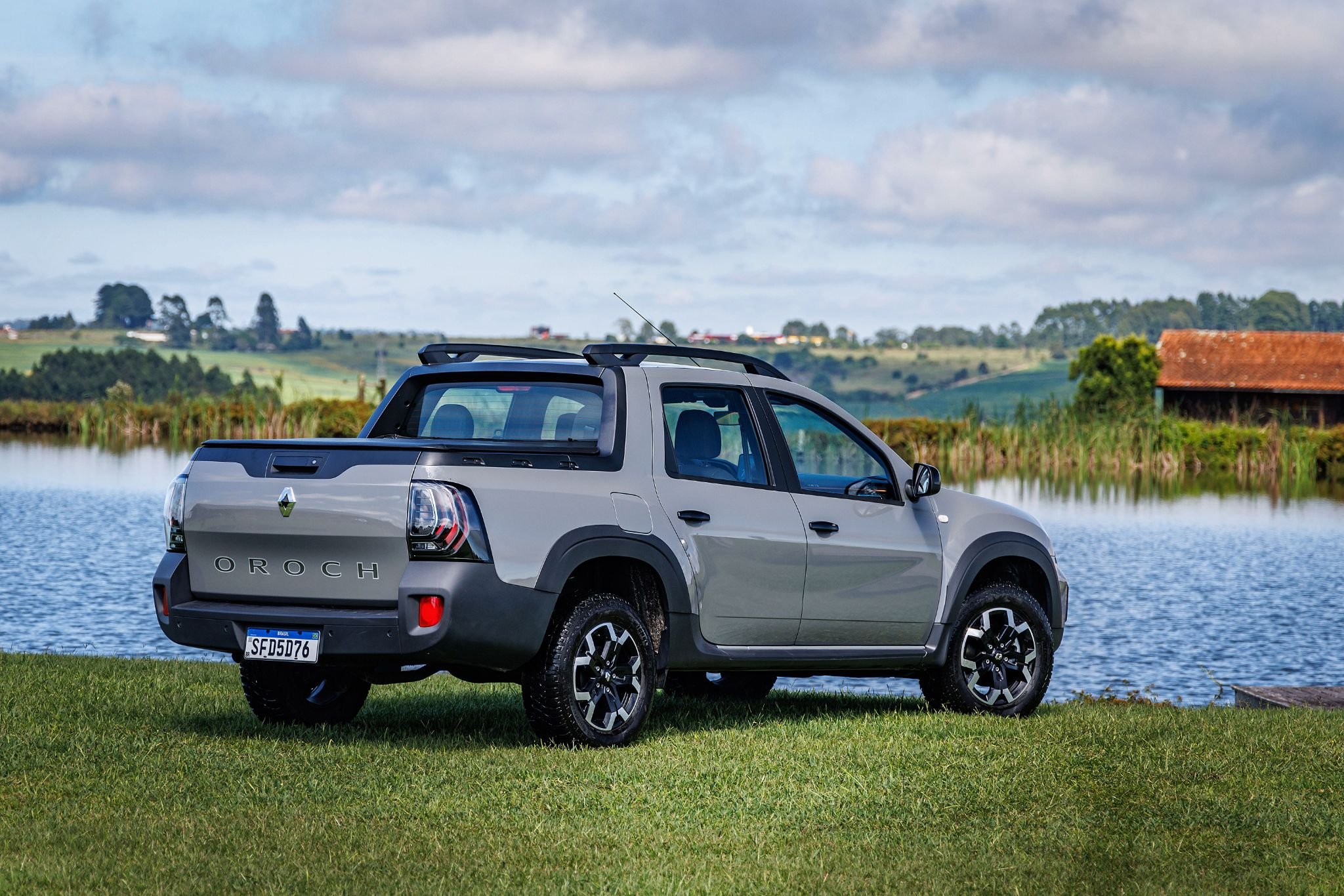 renault oroch iconic 1 6 cinza lune parado traseira em gramado com lago ao fundo