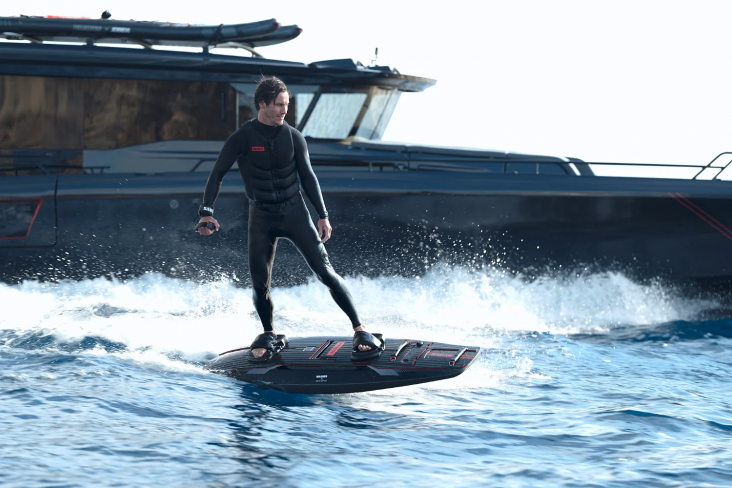 prancha de surf eletrica shadow jetboard brabus awake utilizada por homem surfando com barco ao fundo 1