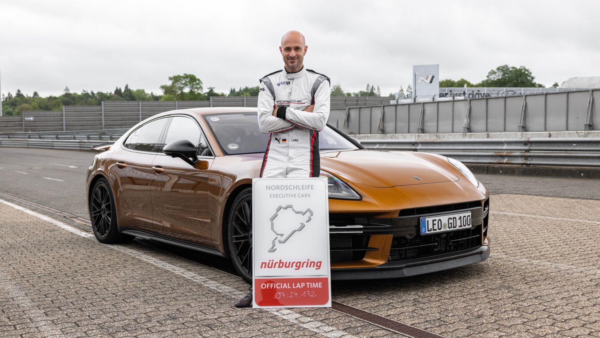 Nova versão porsche panamera nurburgring laranja parado com piloto lars kern