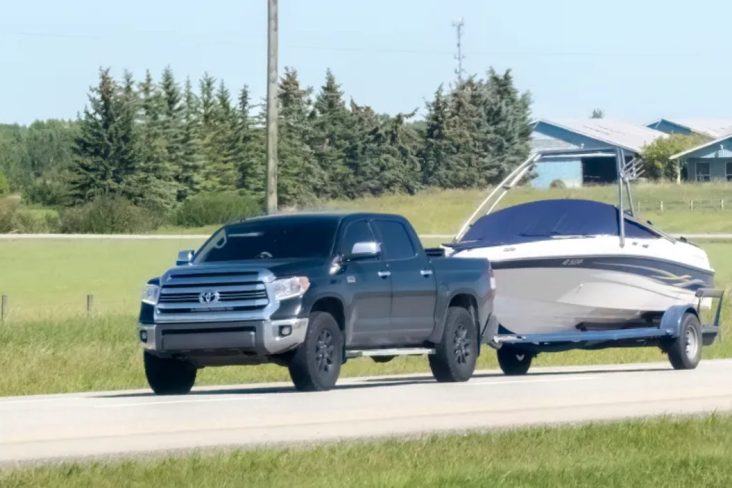 picape toyota preta na estrada com um barco pequeno rebocado (1)