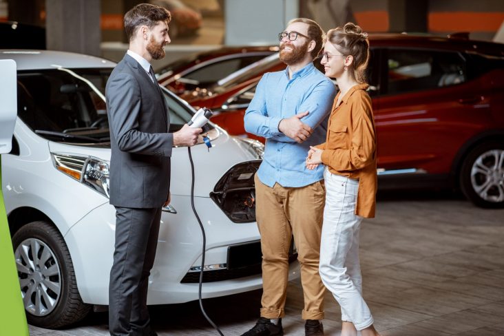 vendedor mostra carro eletrico usado para casal