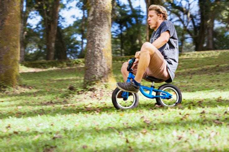 ADULTO PEDALANDO EM BICICLETA INFANTIL DESCENDO LADEIRA SHUTTERSTOCK