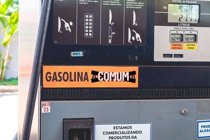 Bomba posto de combustível com gasolina com placa de gasolina aditivada rasurada com escrita comum