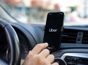 mão de pessoa boa clicando em celular acom logotipo da Uber afixado em painel de carro lista de carros Uber Black Uber Comfort 2025