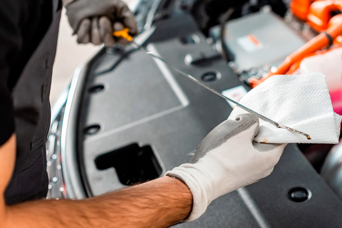 Mão com luva limpando a vareta de óleo com pano limpo