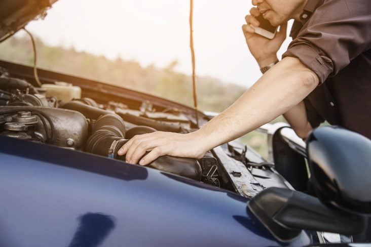 Homem com a mão no motor de combustão