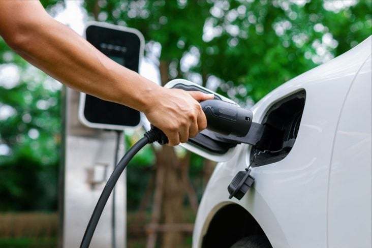 carregadores de carros elétricos mão de pessoa plugando um carregador em carro elétrico ou híbrido plug in branco