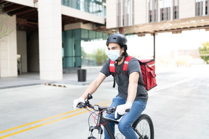 homem de mascara fazendo entrega de bicicleta