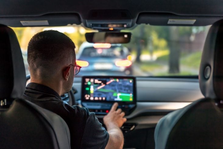 ShutterStock homem mexendo na multimídia de seu carro com tela do Waze PRF parceria com Waze Maps GPS